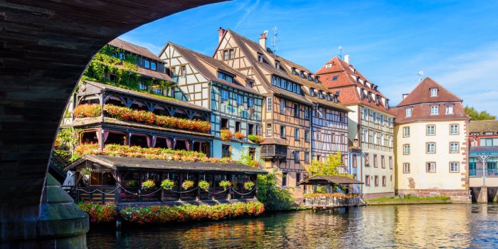 typical half-timbered buildings with pastel facades lining the river ill in the petite france quarter in strasbourg, fran...