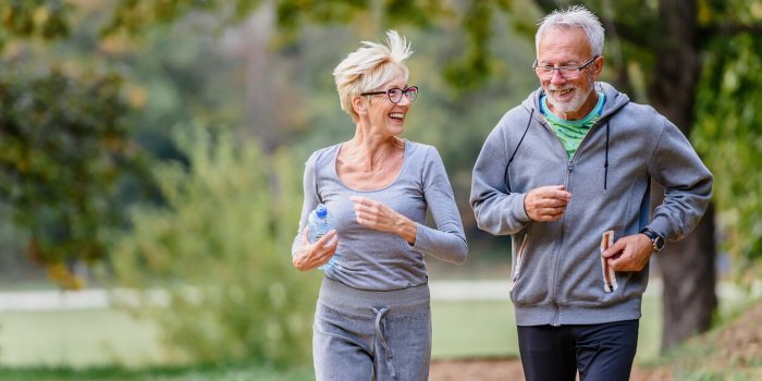 cheerful active senior couple jogging in the park exercise together to stop aging
